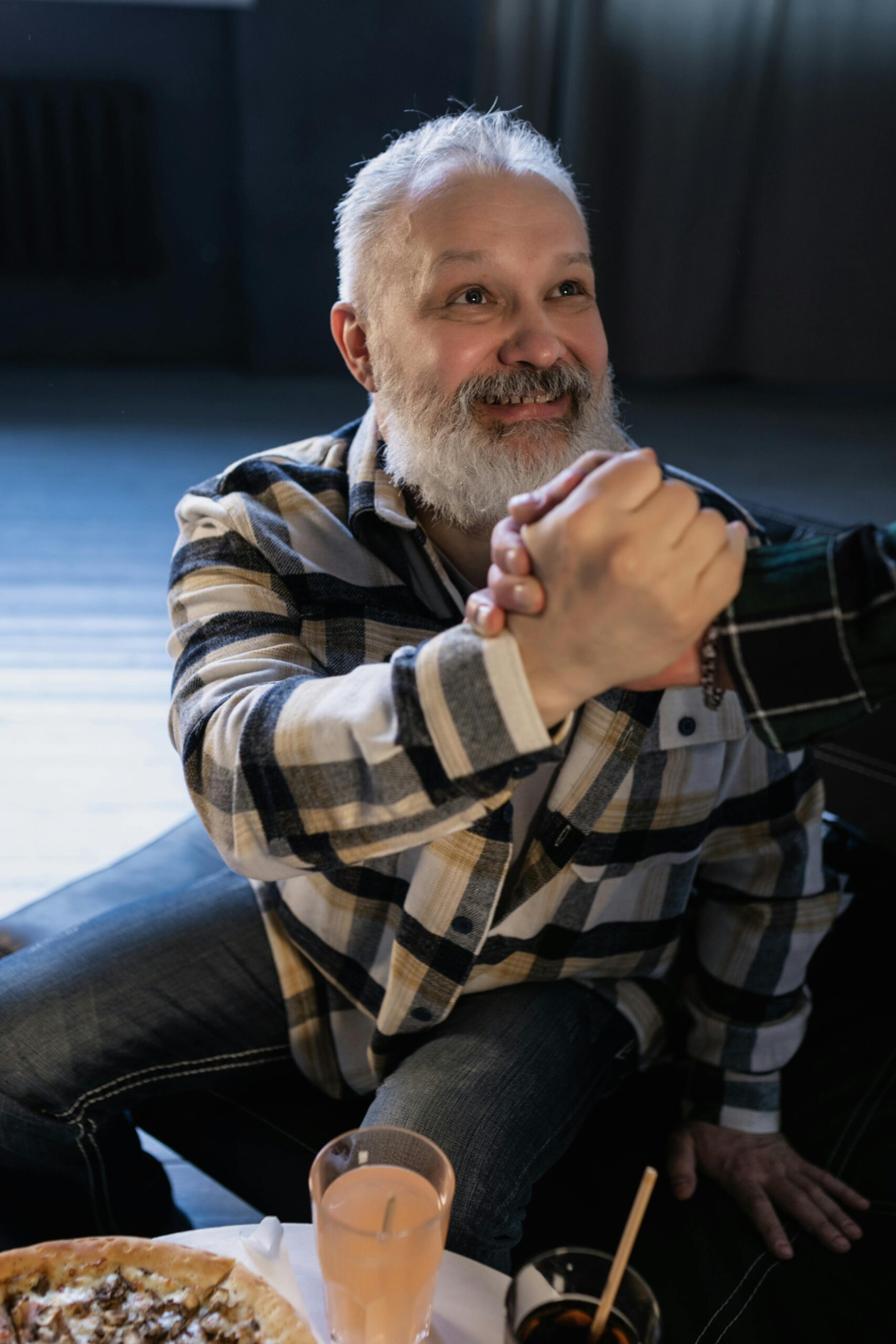 Happy senior man with gray beard shaking hands warmly indoors.